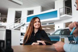Vendedor de concessionária de automóveis explica detalhes do contrato para cliente do sexo feminino
